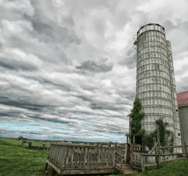 a tall silo stands alone near a river