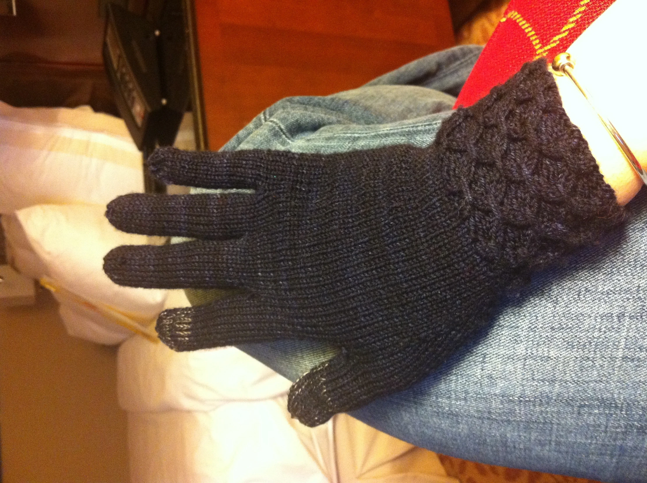 a persons hand with knitted black gloves over it