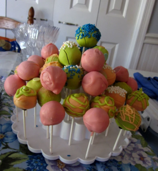 a cake on a stand is topped with pink, blue and green desserts