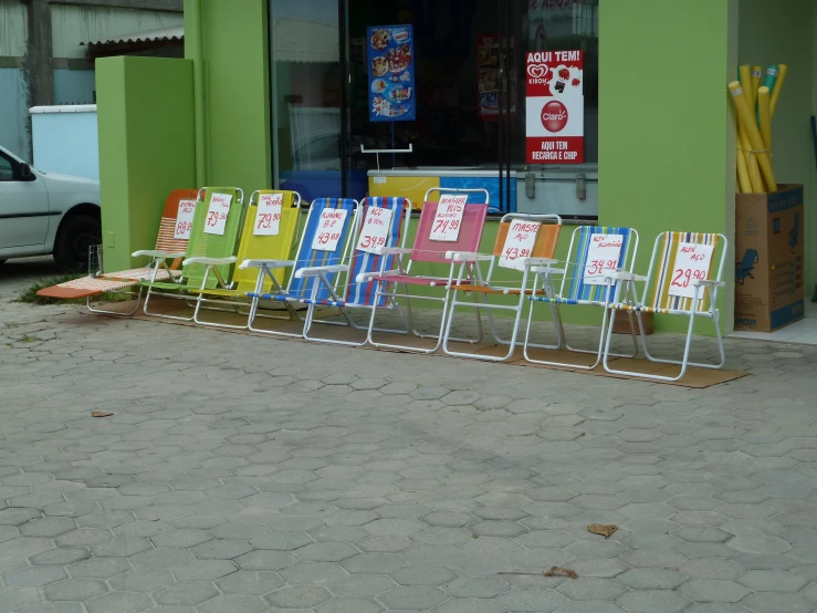 a row of chairs are sitting in front of a small store