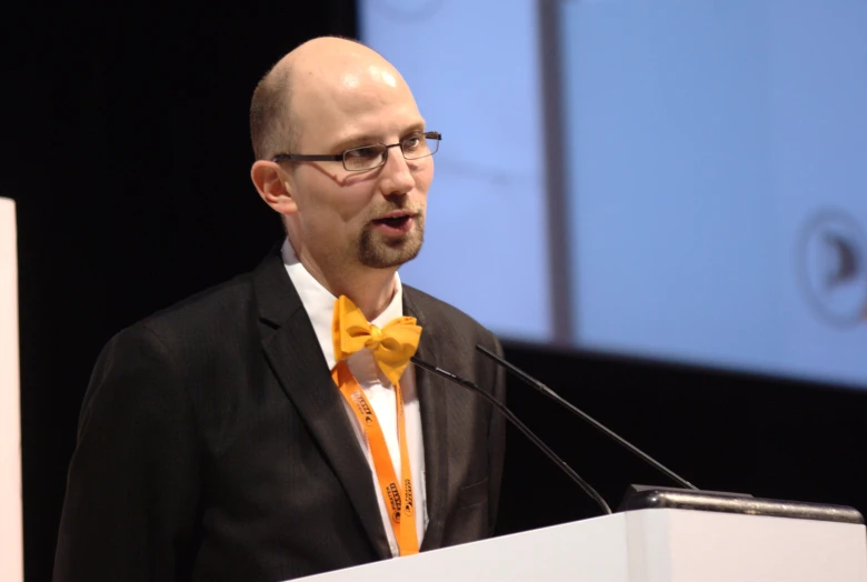 man in black suit wearing orange bow tie