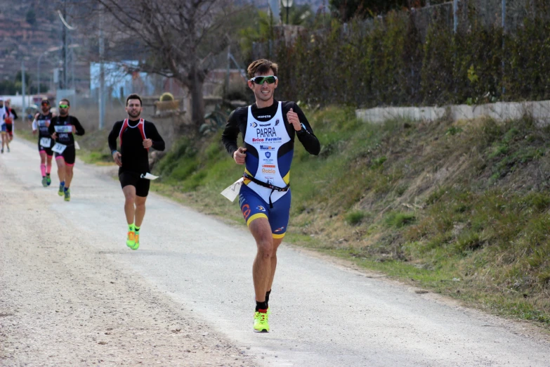 a man wearing a bib running with another man wearing a jacket and shorts