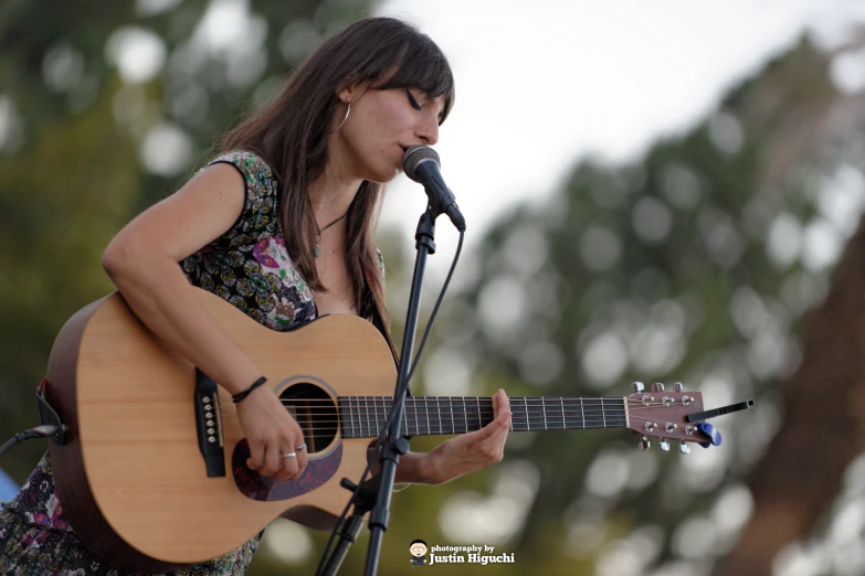 a girl singing and playing the guitar during a concert