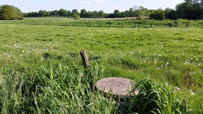 an old metal table is in the middle of the green field