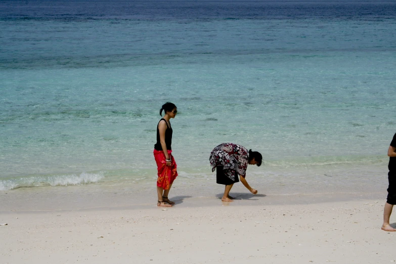 three people walking along the edge of a body of water