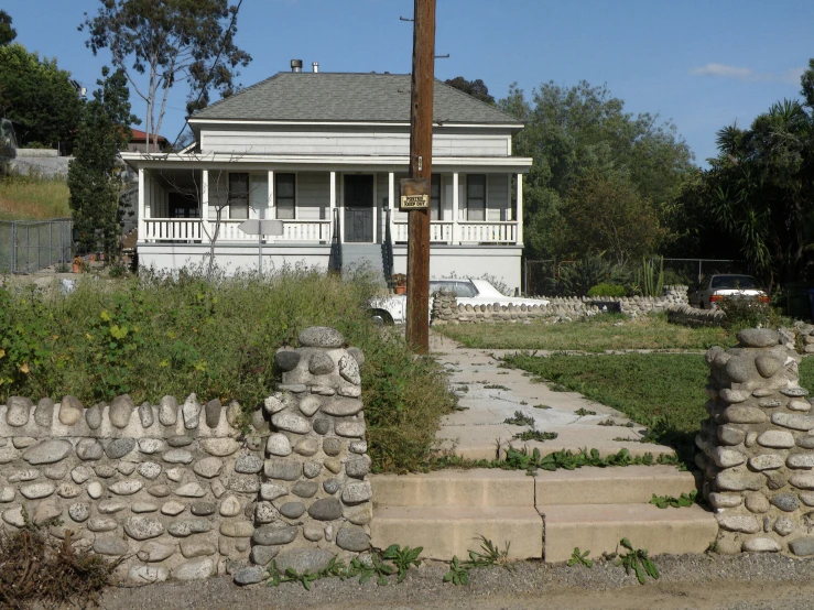 a stone wall in front of a white house