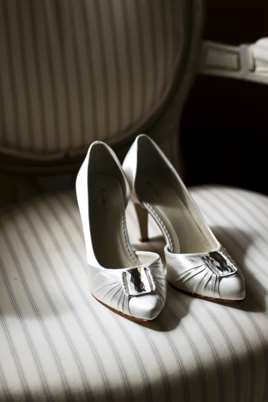 a pair of white high heels sitting on a striped cloth