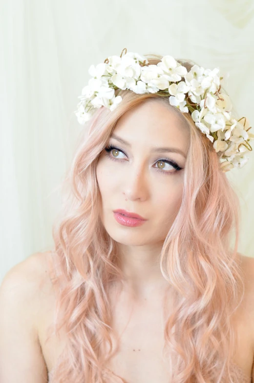 the young woman with long pink hair is wearing a wreath