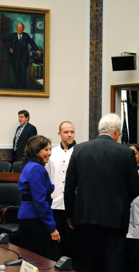 a group of people in suits and ties standing around a table