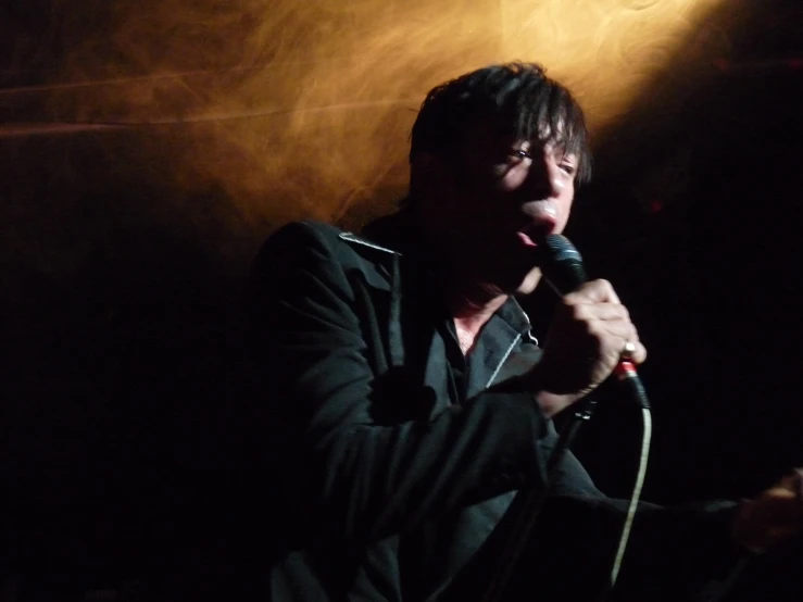 man singing into a microphone in the dark