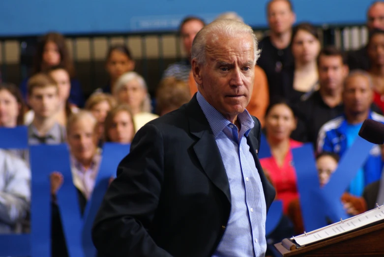 a man speaking to a crowd and holding papers