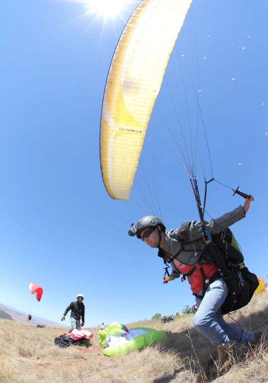 a man wearing a backpack is standing near a large parasailer