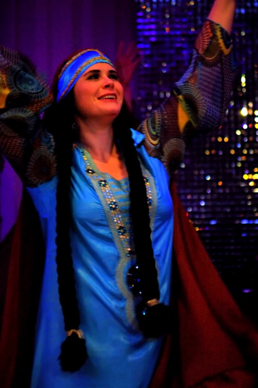 a woman is wearing a blue outfit with colorful accessories on her head