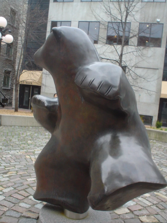 the bear statue is made out of bronze, and has two hands