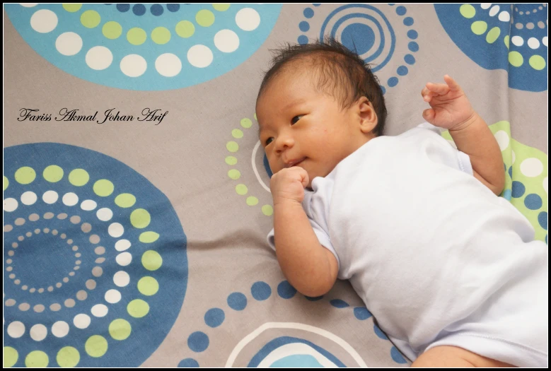 a smiling baby in diapers is lying on a blanket