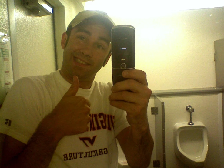 a man in white shirt taking a selfie in a restroom