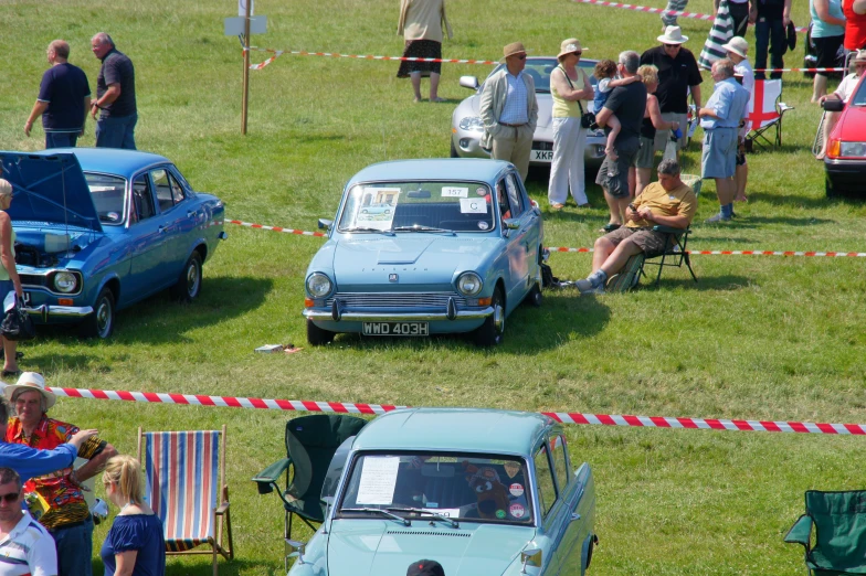 an image of some people looking at old cars