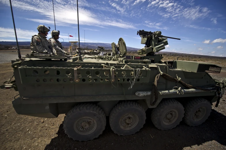 two military men sit on top of an army truck
