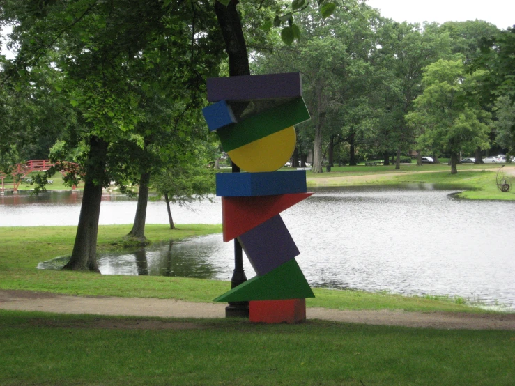 colorful, abstract sculpture on display at park next to a pond