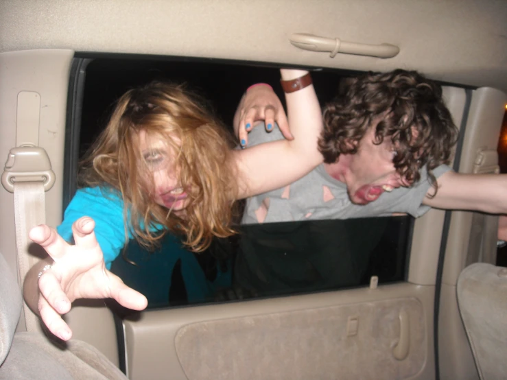 a girl and boy are sitting in a car in the backseat