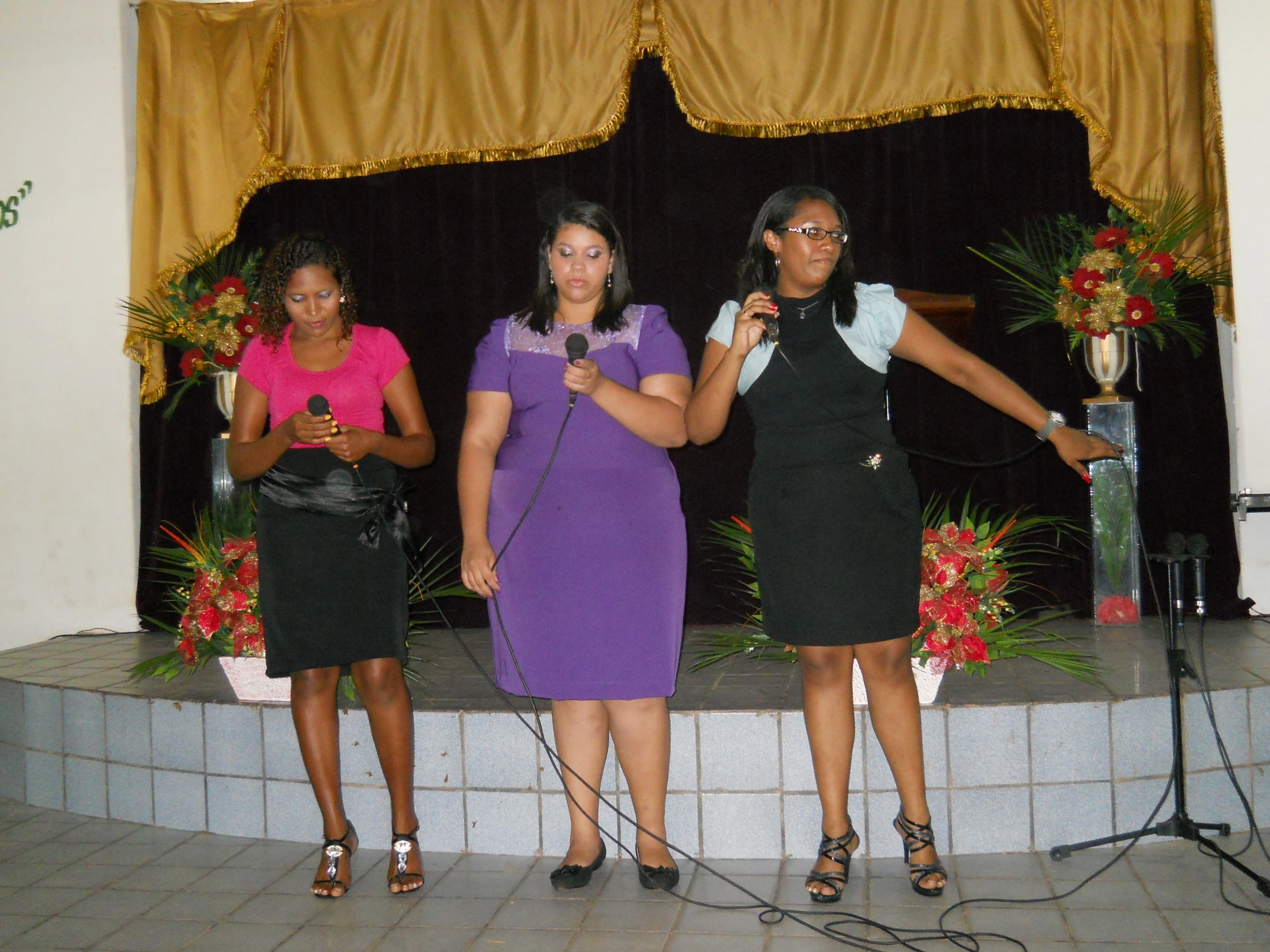 three ladies are singing on stage for the crowd