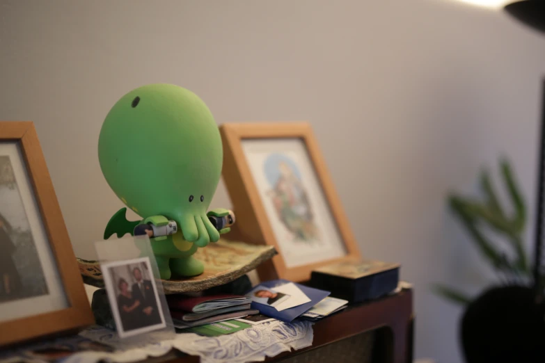 a green toy octo next to a couple pictures