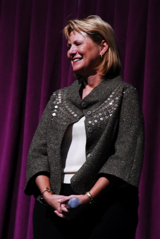 woman standing in front of purple curtains smiling at an event