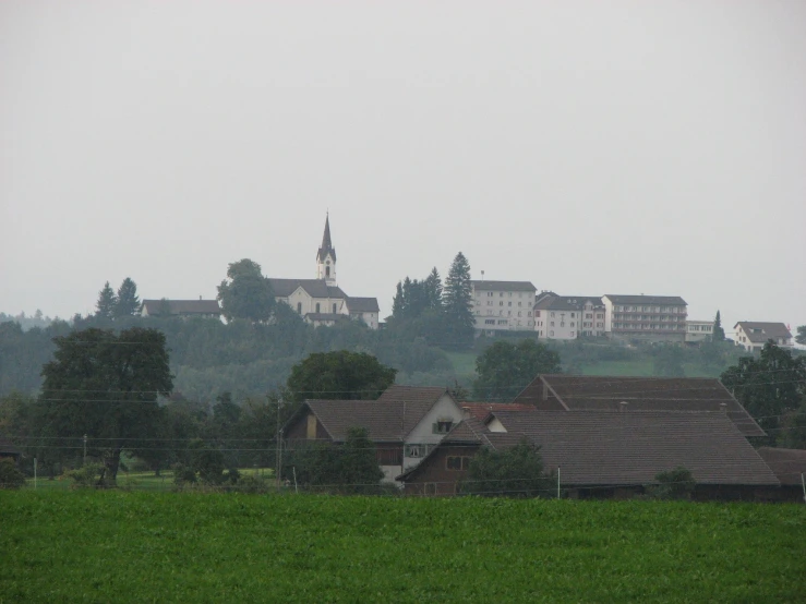 buildings near the field and trees on a hill