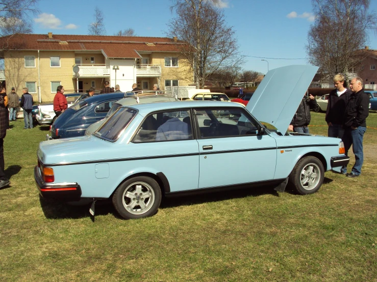 people gather at an outside car show to see cars