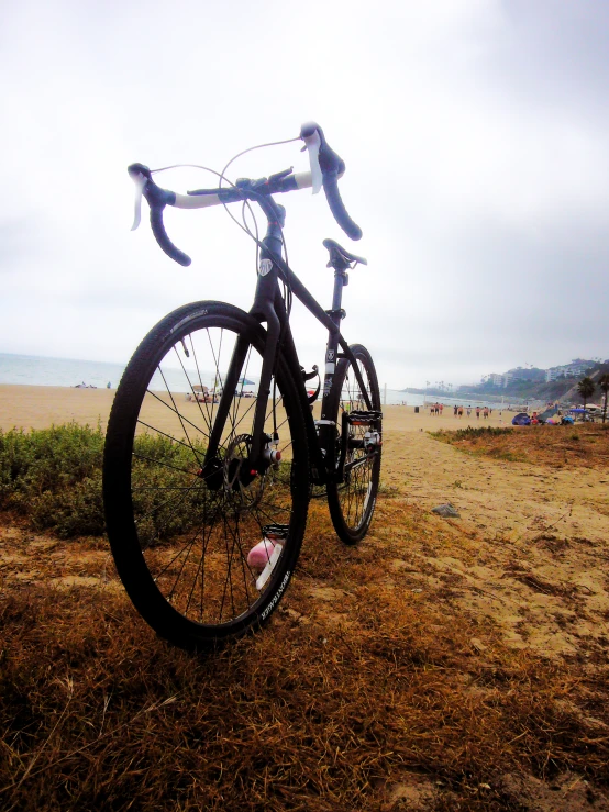 a bike with bars and wheels parked on a dirt field