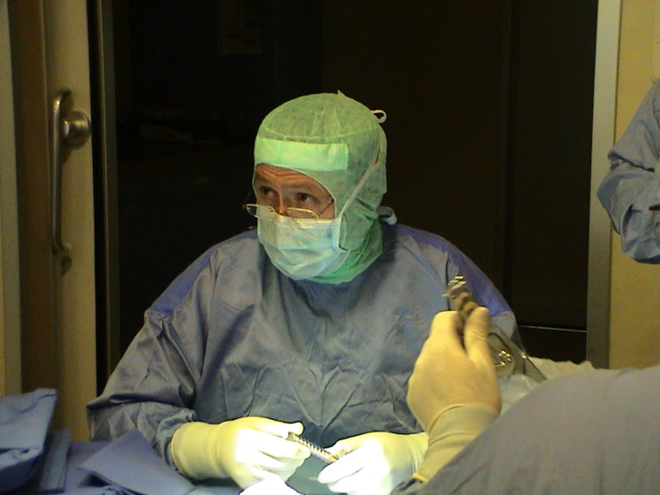 the surgeon in blue covers the eyes with a mask and scissors