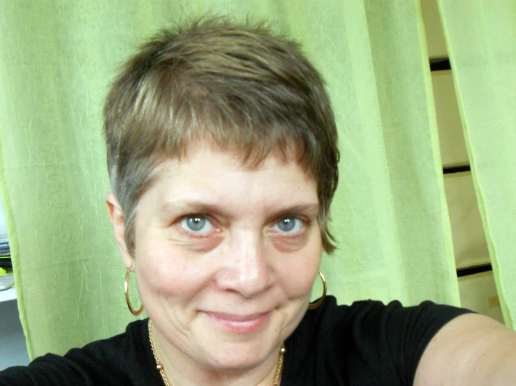 a woman wearing gold earrings and a black shirt