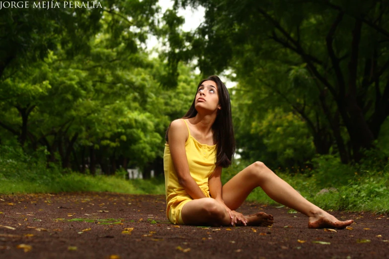 a woman sitting on the ground with trees in the background