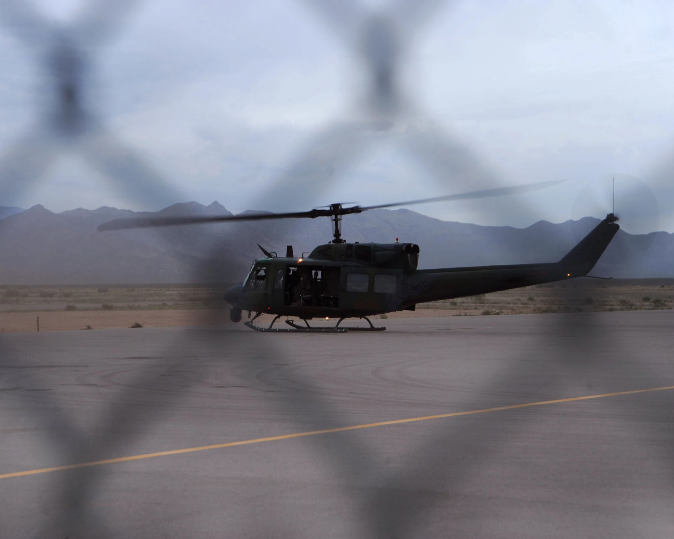 a black helicopter with the wheels down sits in the runway