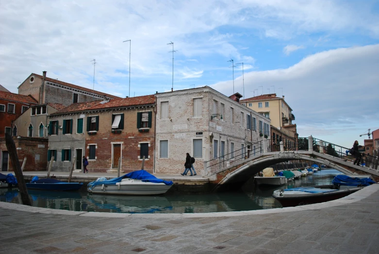 several boats docked along the shore of a river near buildings