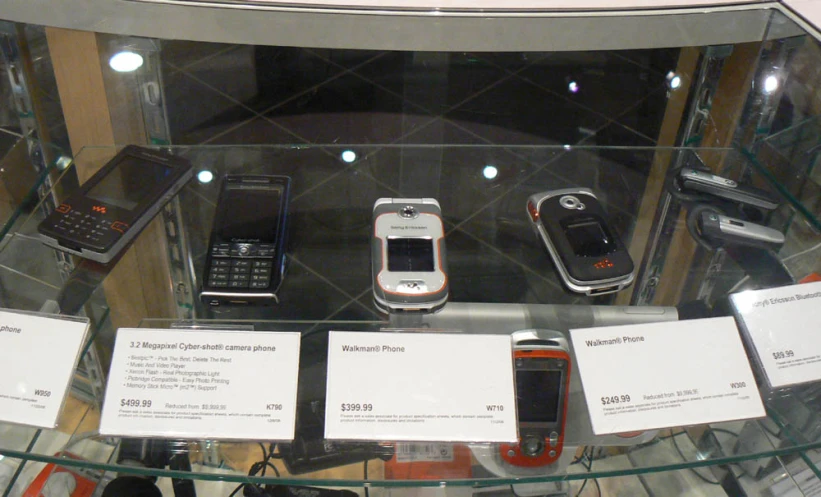 several cell phones on display on glass shelves