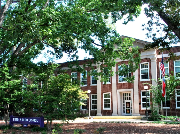 a brown and white building and trees with flags