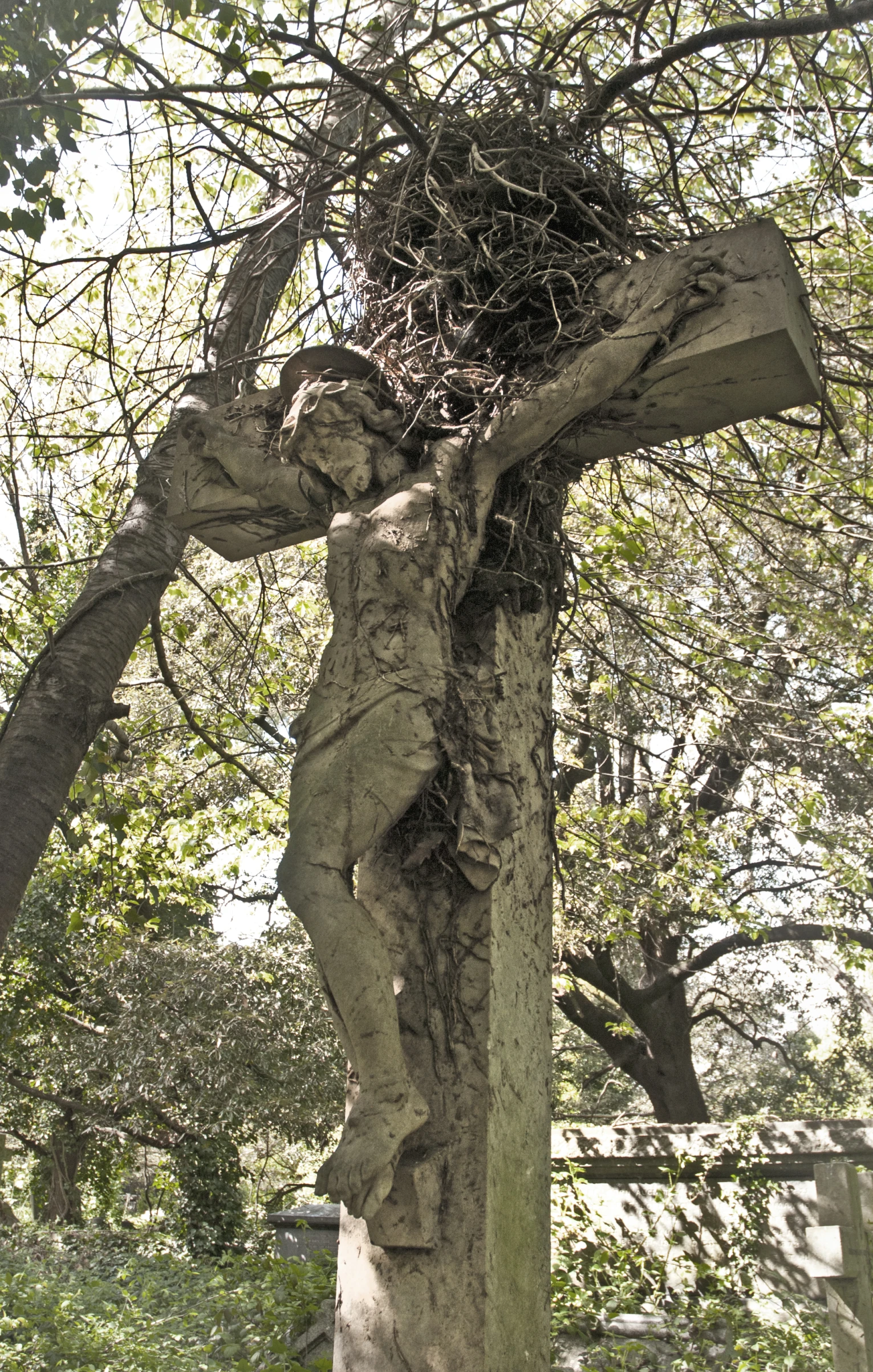 a large stone cross sitting under a tree