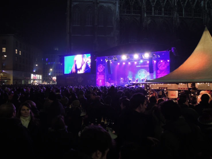 a crowd is gathered to listen music while an image is projected on the screen