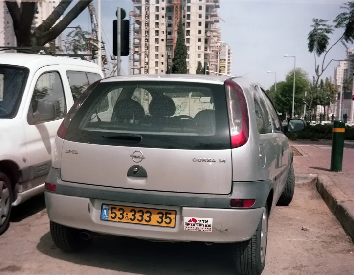 silver nissan parked on city street next to buildings