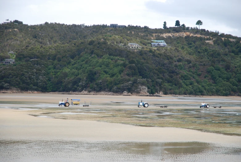 several tractors sitting on some land near water