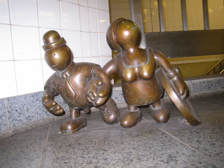 a statue is sitting on the ground near a brick wall