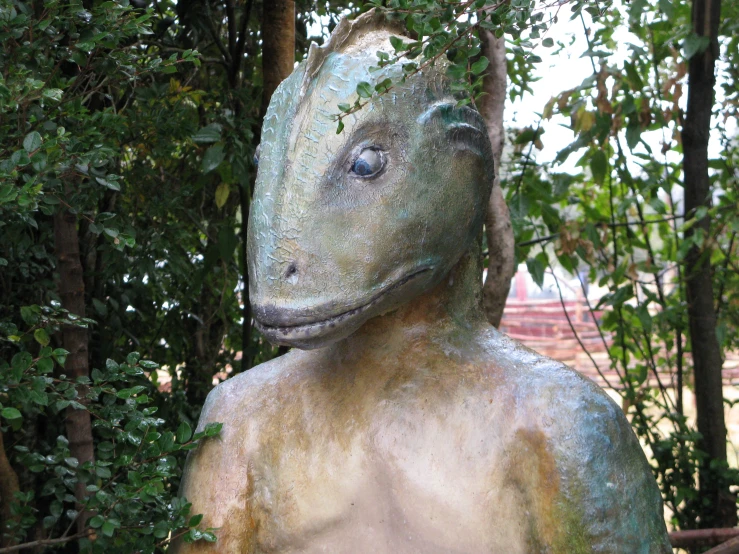a statue of a lizard has its head obscured by green leaves