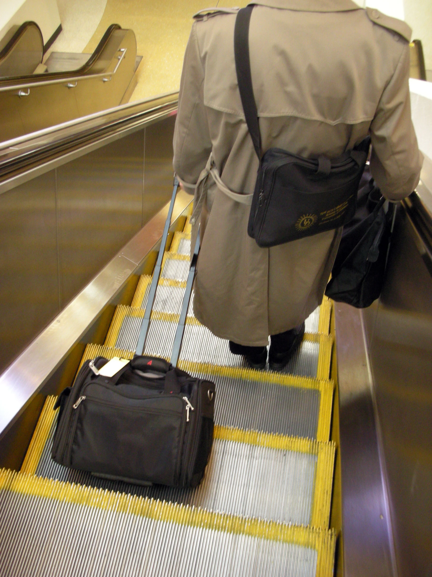 the back end of a person hing luggage down an escalator