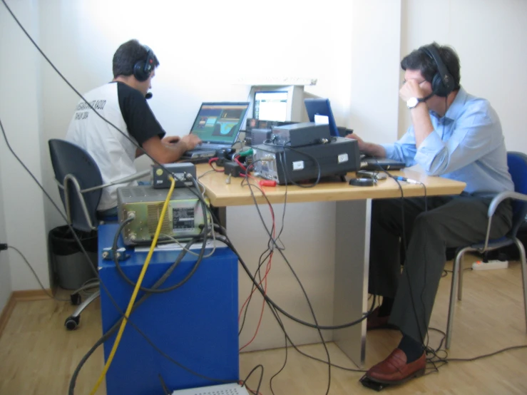 two men sitting at a table with their laptops