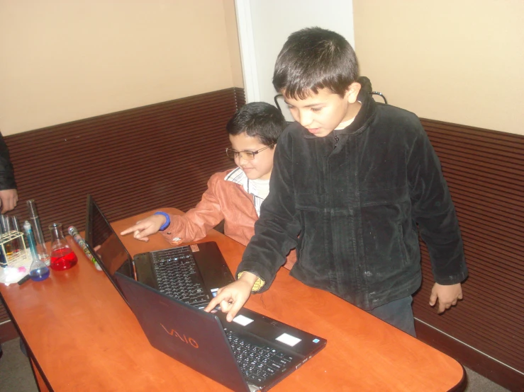 two s using laptop computers at a wooden desk