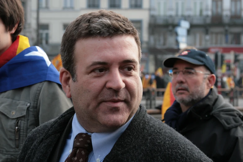 a man in coat and tie talking on street