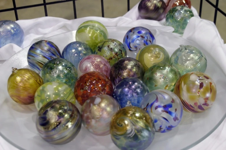 there are dozens of multi colored glass balls on the glass plate