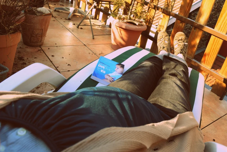 the legs and knees of a man on a deck with potted plants