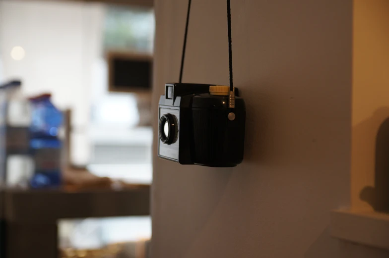 the black camera is mounted on the wall by a cord